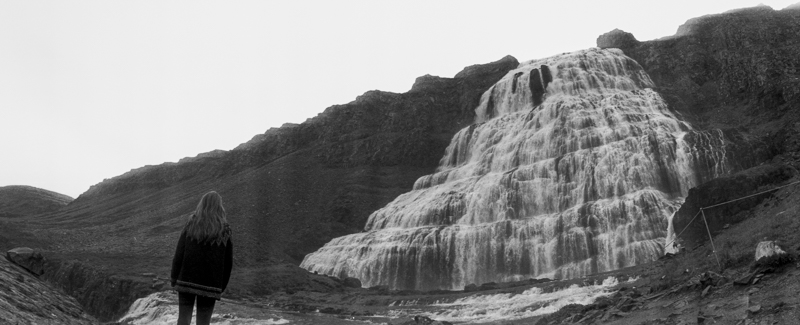 Panoramic photo of a girl in front of a waterfall